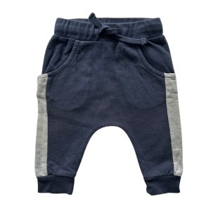 Pantalon de jogging bleu marine avec bande verticale grise sur chaque côté, de la longueur des poches aux chevilles. Deux poches latérales, resserré aux cheville. Resserré à la taille par un lacet bleu marine en tissu. Marque Pommette 6 mois, d'occasion