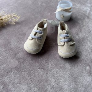 Paire de petites chaussures bébé beige avec lacets blancs, d'occasion