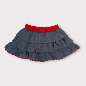 Jupe bébé en jean bleu avec ceinture élastiquée orange et volants superposés. Seconde main.