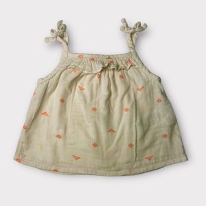 Débardeur bébé beige à fines bretelles nouées, avec volants sur le devant et petits motifs abricot. Seconde main.