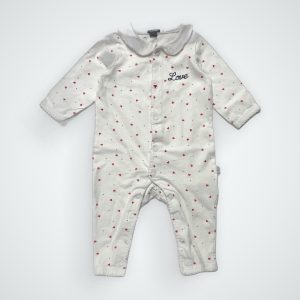 Combinaison bébé blanche à manches longues avec motifs petits cœurs, fermeture à bouton-pression sur le devant avec un col claudine. Seconde main.