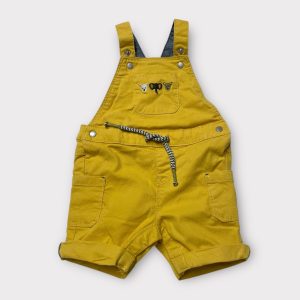 Salopette courte bébé moutarde avec poches sur les jambes et sur le tablier, dotée de pressions entre les jambes. Seconde main.