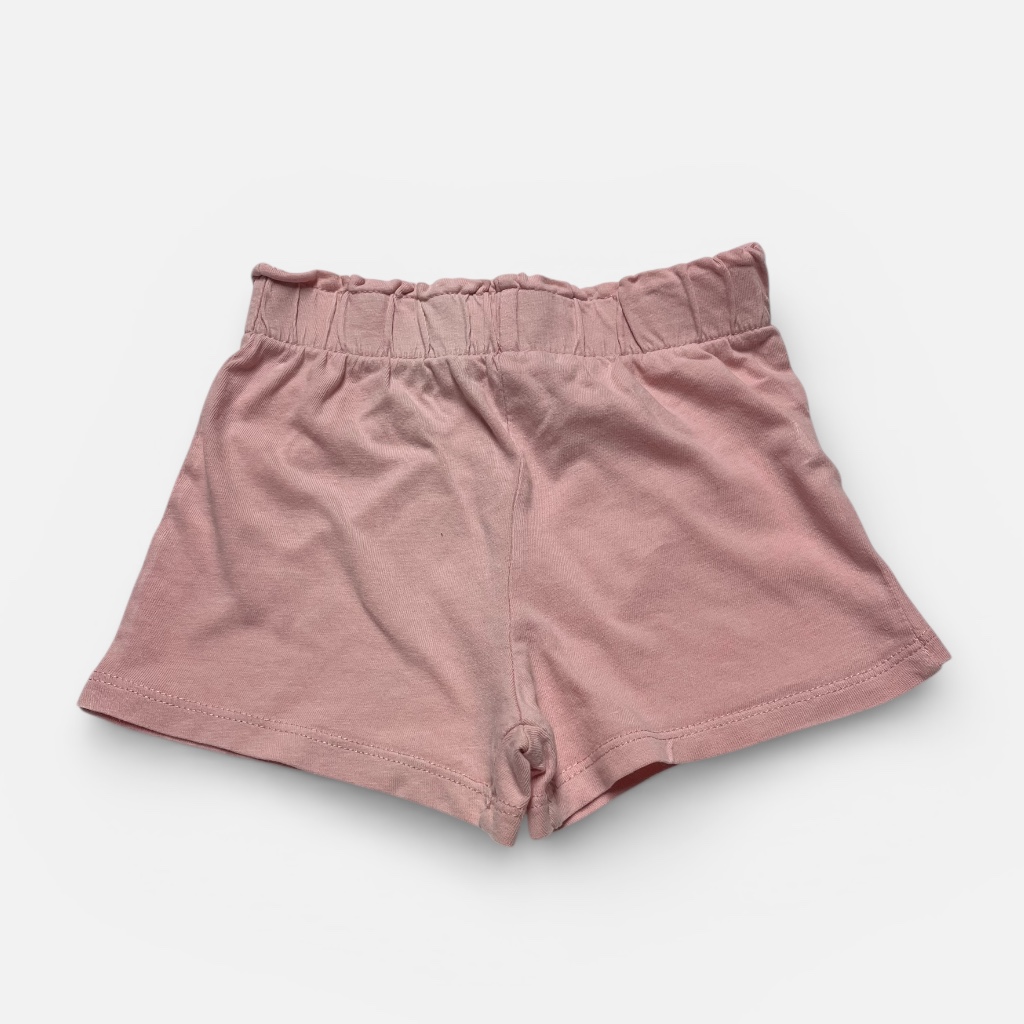 Short bébé en maille pêche, élastiqué à la taille. Seconde main.